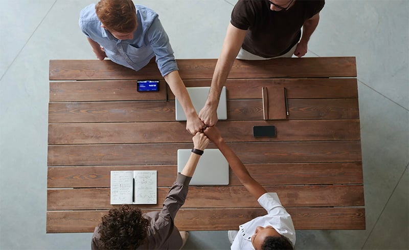 Group of people fist-bumping over a table